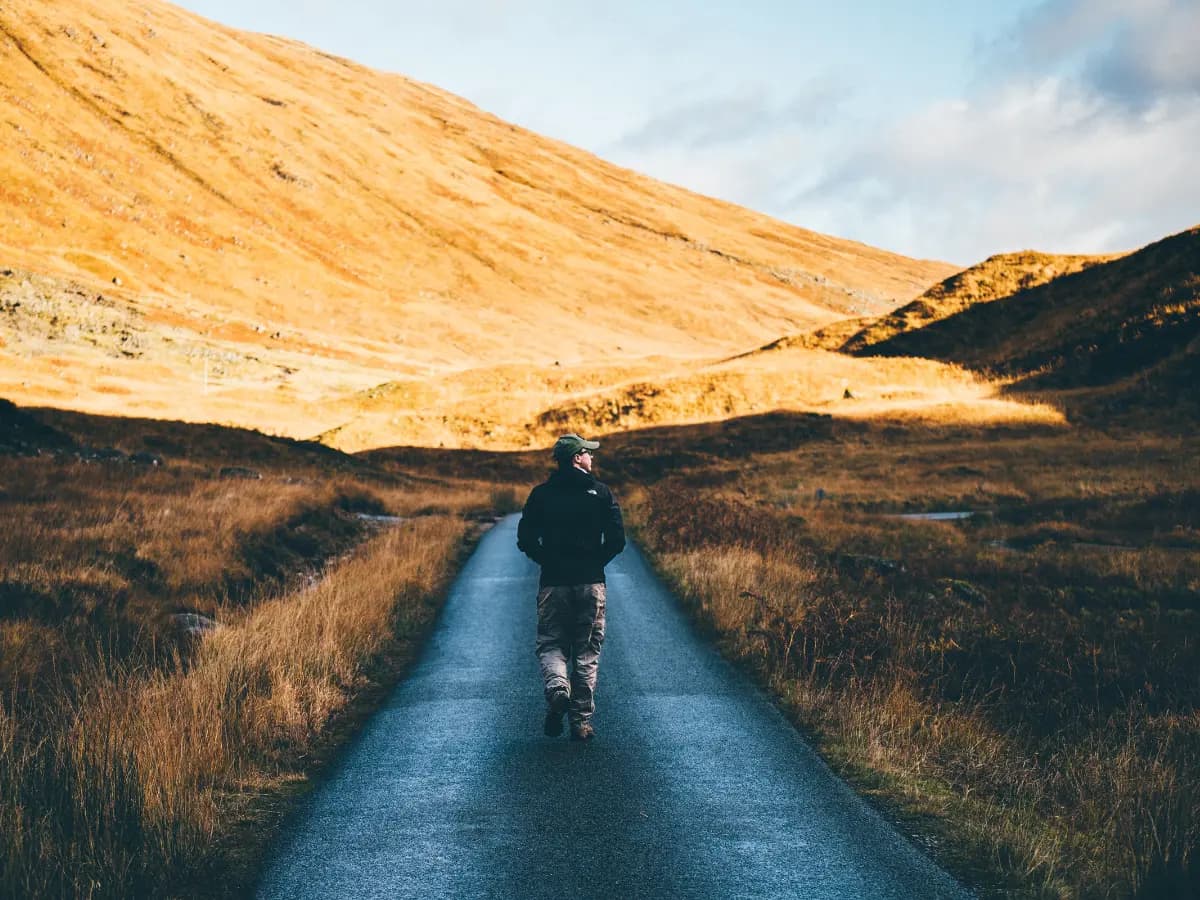 Hiker walking on a mountain road at sunset - representing the Trailkeep journey.