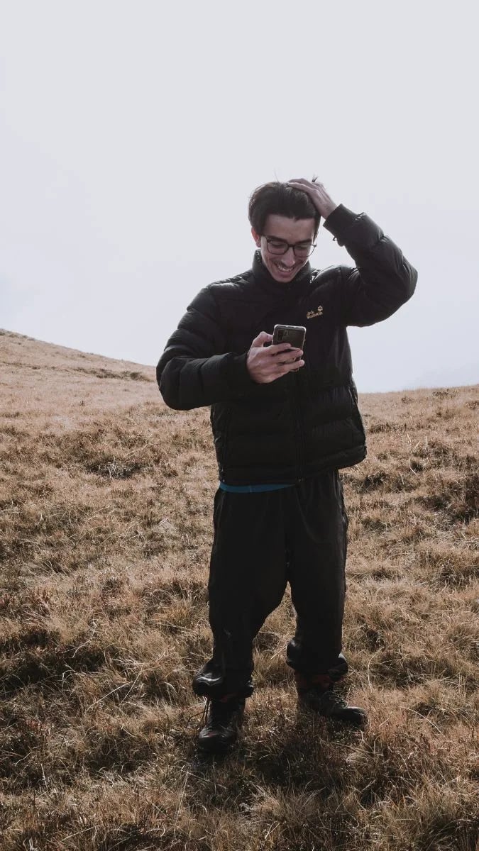 Hand holding a phone in the wilderness.